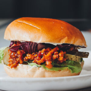 veganer Burger auf hellem Teller vor dunklem Hintergrund